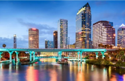 Downtown Tampa Bay skyline at sunset featuring waterfront reflections and high-rise office buildings, highlighting the Tampa Bay business community.