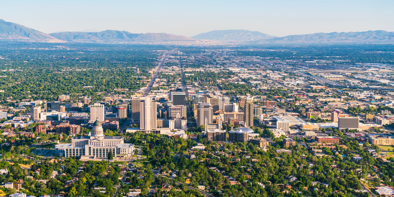 A wide view of the Salt Lake City skyline highlighting the downtown business district with the Wasatch Mountains in the background, representing the region’s growing technology and business environment.