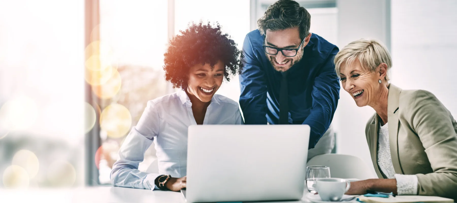 Three people looking at a computer smiling