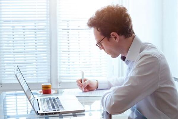 Professional man working at a laptop and taking notes, showcasing the answer to what are special skills and ability to define: what are special skills?