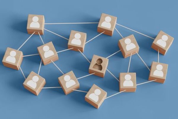 Wooden blocks connected by strings representing team members, with one block showing two figures symbolizing staffing issues and team imbalance.